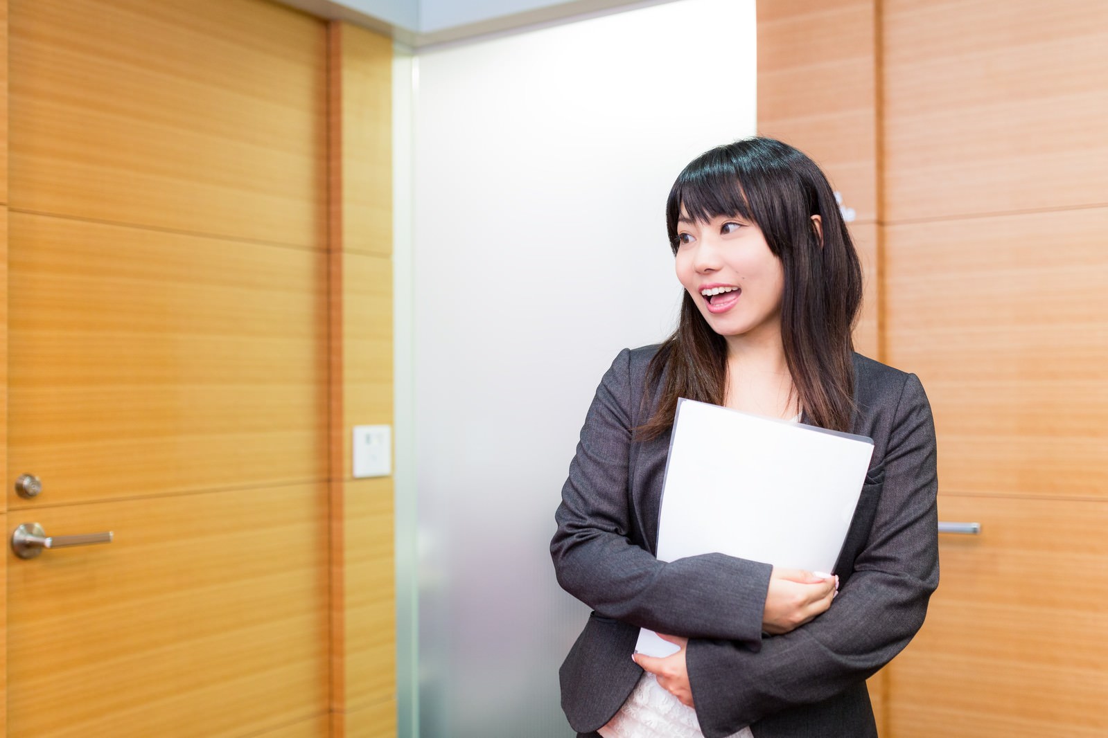 This column highlights the Japanese view on greetings, along with a well-known remark by a Japanese comedian. The featured image shows a young female business professional arriving at the office and greeting her colleagues.