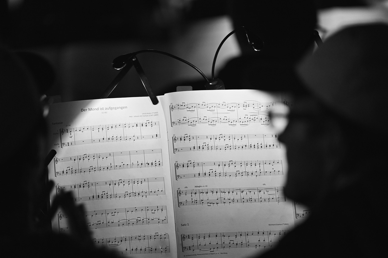 A close-up photo of sheet music on a music stand illuminated at a performance venue, used as a featured image for an article on Japan’s introduction of record performance and communication rights.